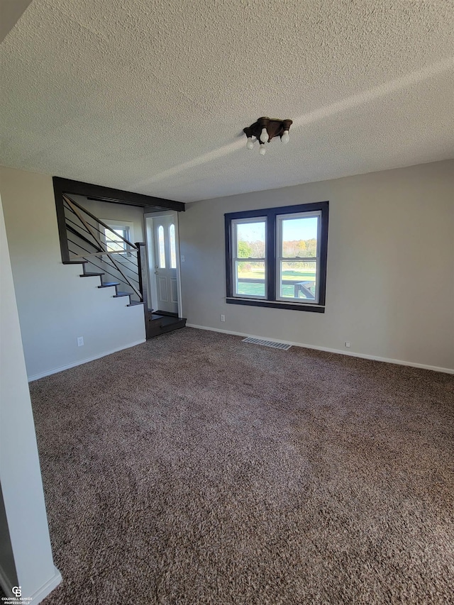 carpeted empty room featuring a textured ceiling