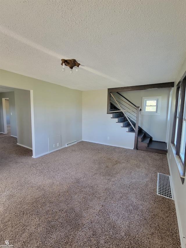 unfurnished living room with a textured ceiling and carpet flooring