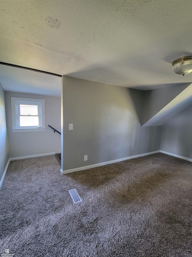 bonus room with a textured ceiling and carpet floors