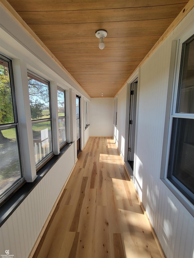 corridor featuring light hardwood / wood-style floors and wooden ceiling