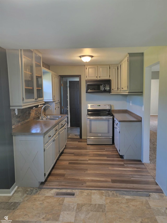 kitchen featuring stainless steel range with electric stovetop, tasteful backsplash, sink, and dark wood-type flooring