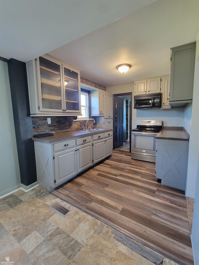 kitchen with hardwood / wood-style flooring, stainless steel range with electric stovetop, decorative backsplash, and sink