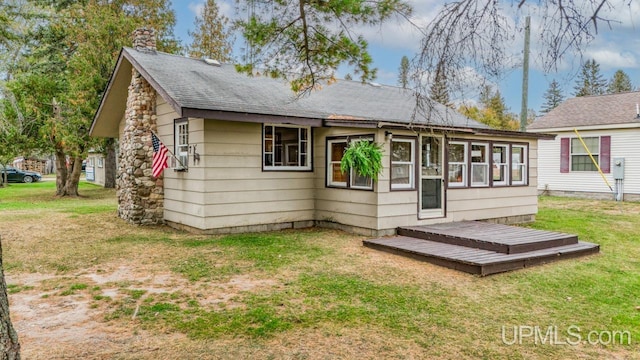 rear view of house with a deck and a yard