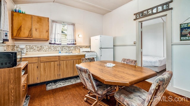 kitchen featuring white appliances, sink, lofted ceiling, and dark carpet