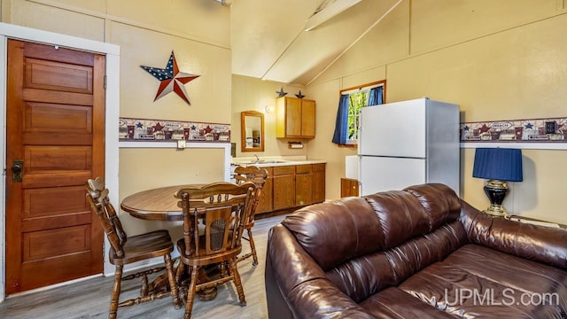 dining room featuring sink, light hardwood / wood-style floors, and vaulted ceiling