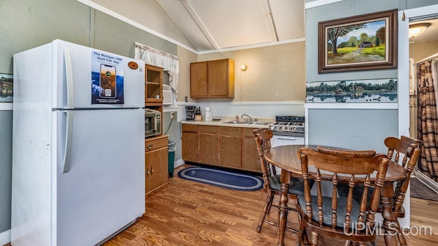 kitchen with light hardwood / wood-style floors, white fridge, sink, and vaulted ceiling