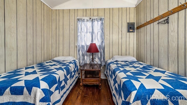 bedroom with wood walls, vaulted ceiling, and dark hardwood / wood-style flooring