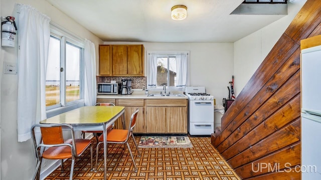 kitchen featuring white appliances, decorative backsplash, and sink