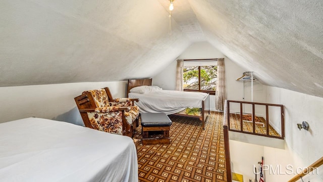 bedroom with parquet floors, a textured ceiling, and lofted ceiling