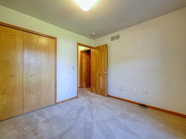 unfurnished bedroom with a closet and light carpet