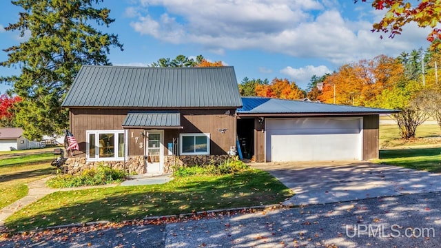 view of front of property featuring a garage, concrete driveway, a front lawn, stone siding, and metal roof