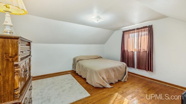 bedroom featuring vaulted ceiling, baseboards, and wood finished floors
