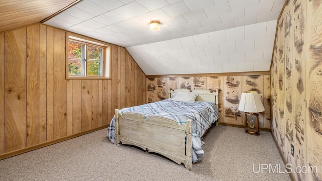 bedroom with lofted ceiling, wooden walls, baseboards, and carpet