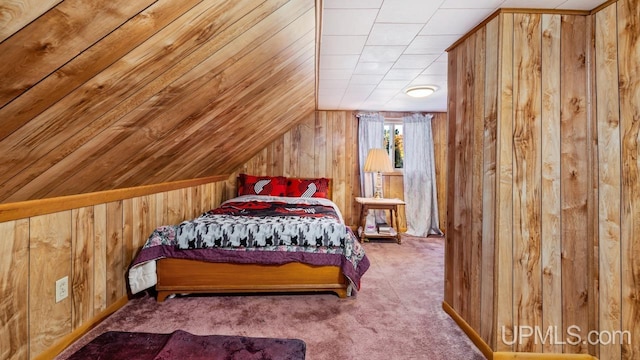 carpeted bedroom with vaulted ceiling and wooden walls