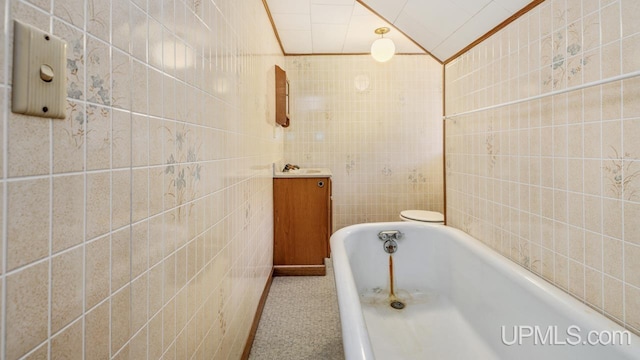 bathroom with a tub, crown molding, tile walls, and lofted ceiling