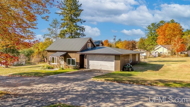 ranch-style home with a garage, metal roof, a front yard, and concrete driveway