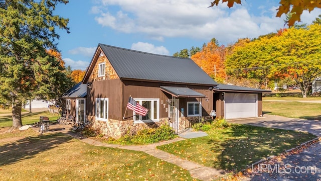 rustic home featuring stone siding, concrete driveway, a front yard, and metal roof