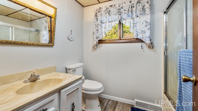 full bath featuring toilet, visible vents, a shower with door, wood finished floors, and vanity