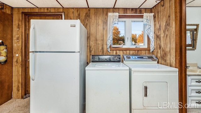 laundry area with carpet floors, wooden walls, and washer and dryer