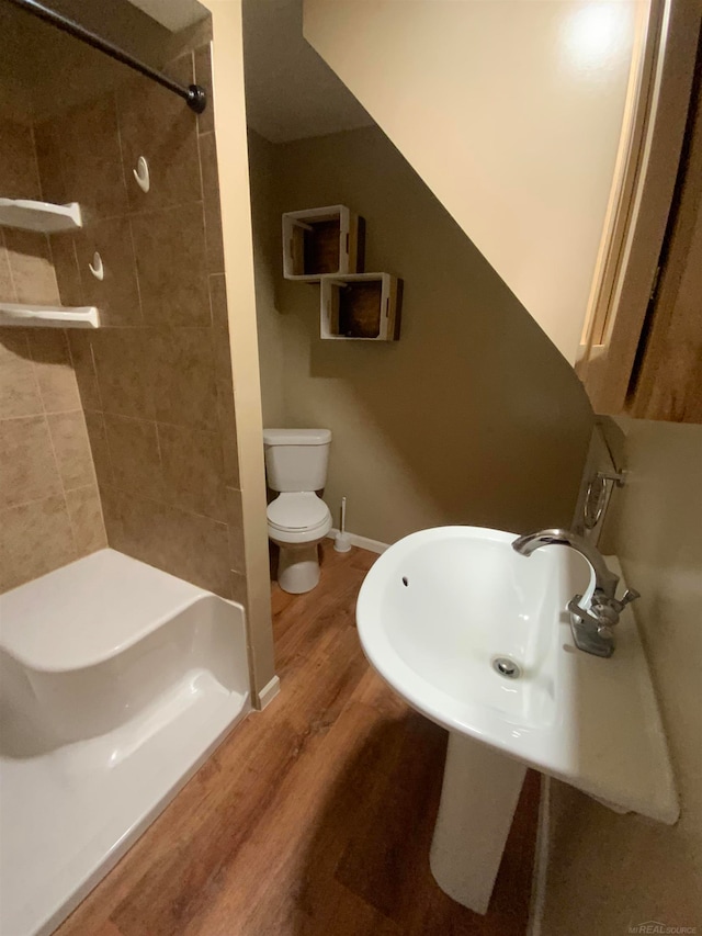 bathroom featuring tiled shower, wood-type flooring, and toilet