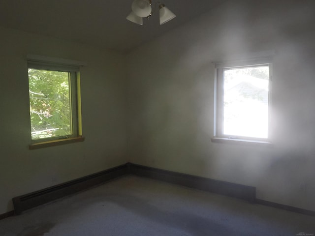 carpeted empty room with a baseboard heating unit, ceiling fan, and plenty of natural light