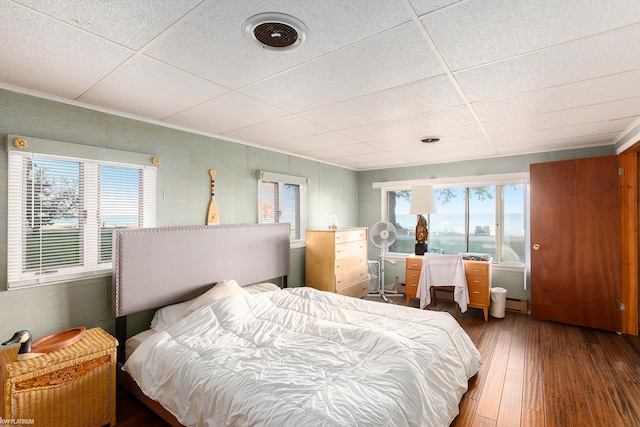 bedroom featuring a drop ceiling and hardwood / wood-style flooring