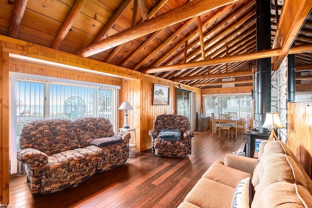 living room featuring wood walls, a wood stove, wood-type flooring, and vaulted ceiling with beams