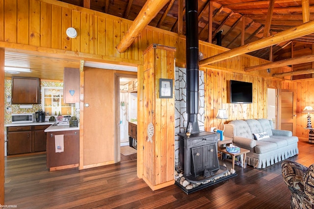 living room featuring a healthy amount of sunlight, a wood stove, dark hardwood / wood-style flooring, wooden walls, and high vaulted ceiling