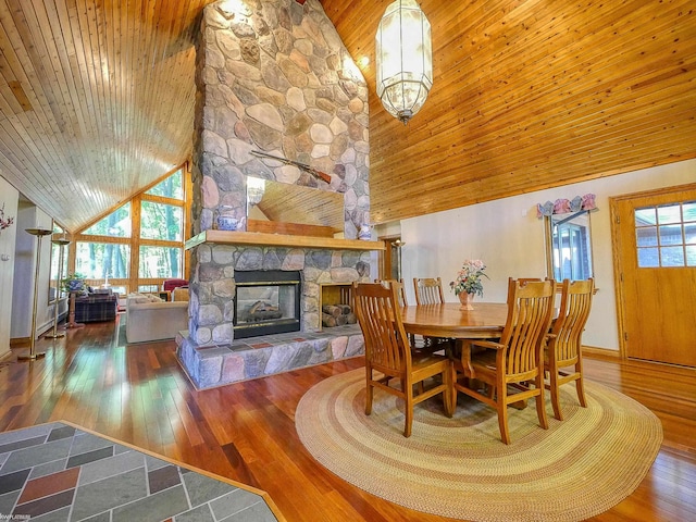 dining space with a wealth of natural light, a stone fireplace, and high vaulted ceiling