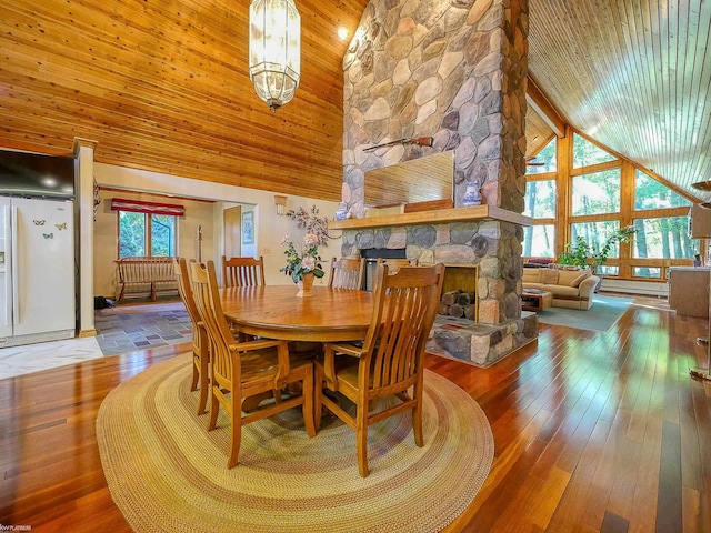 dining space featuring plenty of natural light, a stone fireplace, and high vaulted ceiling