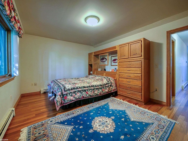 bedroom with hardwood / wood-style floors and a baseboard heating unit