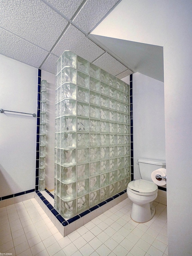 bathroom featuring a shower, tile patterned floors, a drop ceiling, and toilet