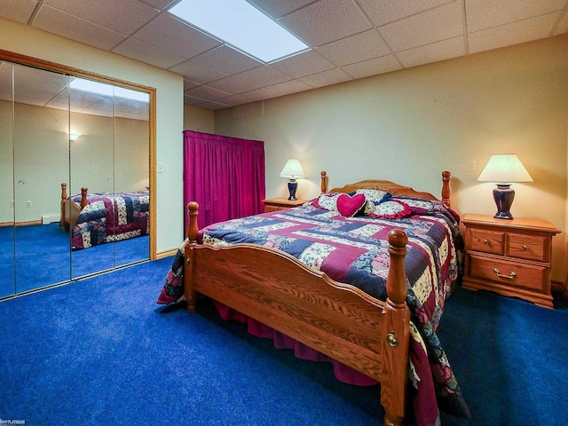 carpeted bedroom with a drop ceiling and a closet