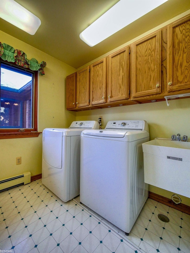 clothes washing area featuring cabinets, baseboard heating, washer and dryer, and sink