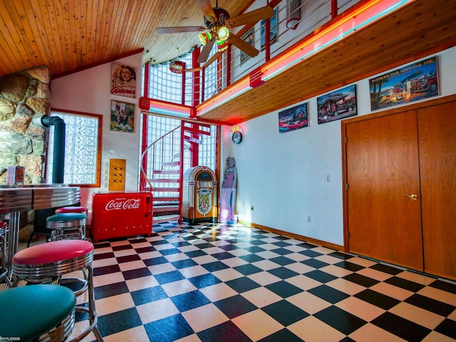 interior space with bar, a wood stove, ceiling fan, and wood ceiling