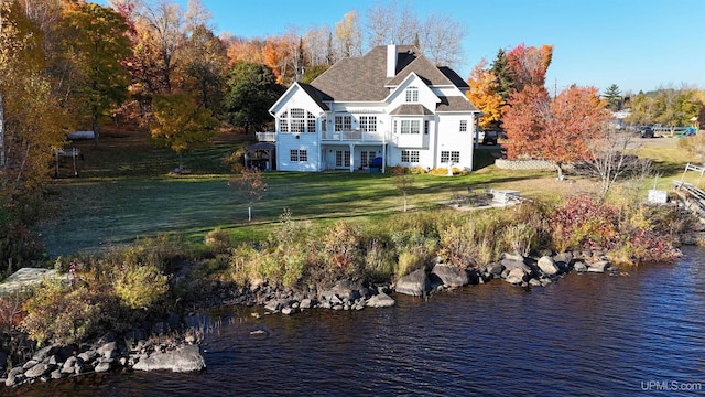 back of house with a yard and a water view