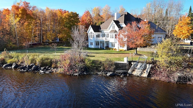 exterior space with a lawn, a chimney, and a water view