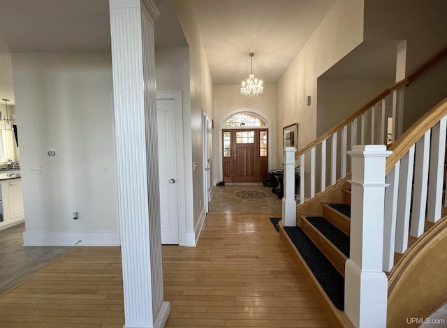 entrance foyer with baseboards, stairway, hardwood / wood-style flooring, and a notable chandelier
