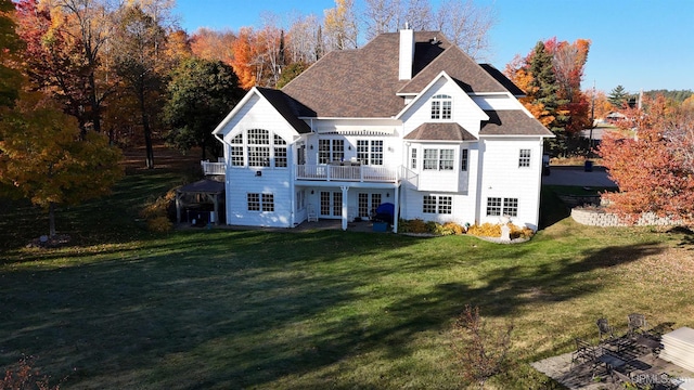 back of house featuring french doors, a chimney, a lawn, a shingled roof, and a deck