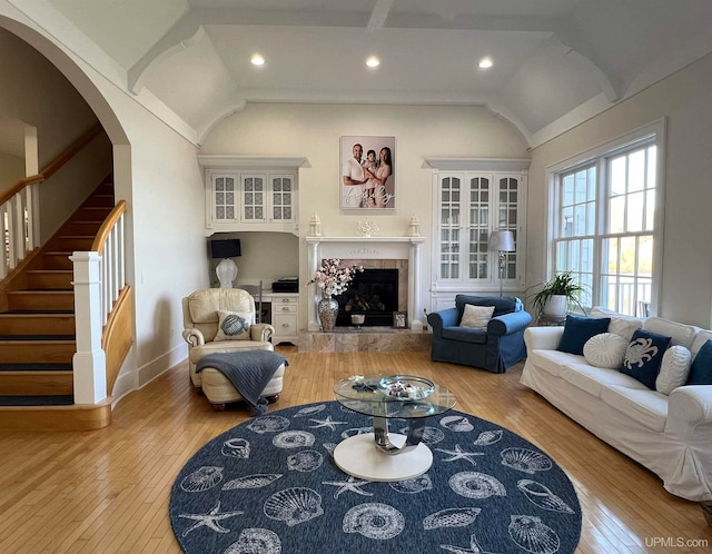 living room with lofted ceiling, a tiled fireplace, and light wood-type flooring