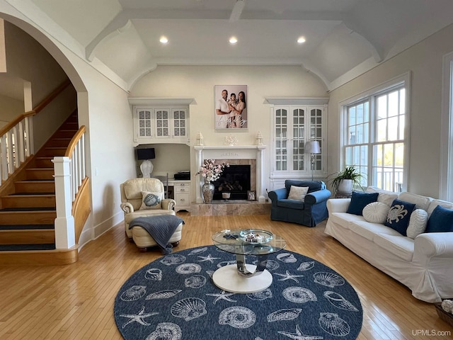 living room featuring lofted ceiling, a tile fireplace, and light wood-type flooring