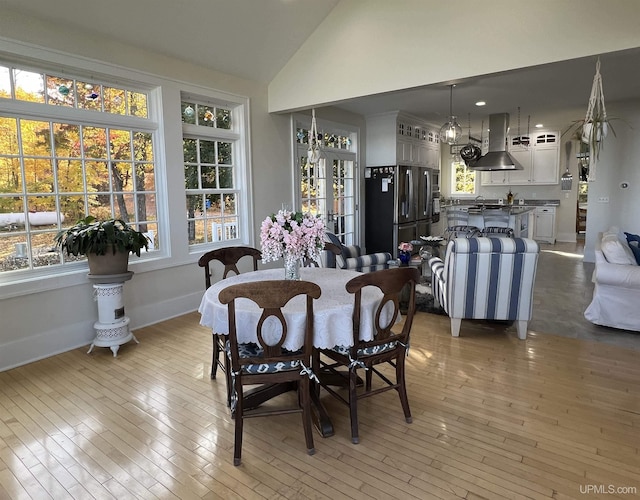 dining room with vaulted ceiling, light wood finished floors, and baseboards