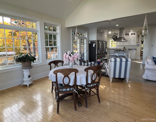 dining space with light wood-type flooring and vaulted ceiling