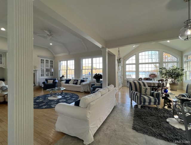 living room with lofted ceiling, a wealth of natural light, a ceiling fan, and ornate columns