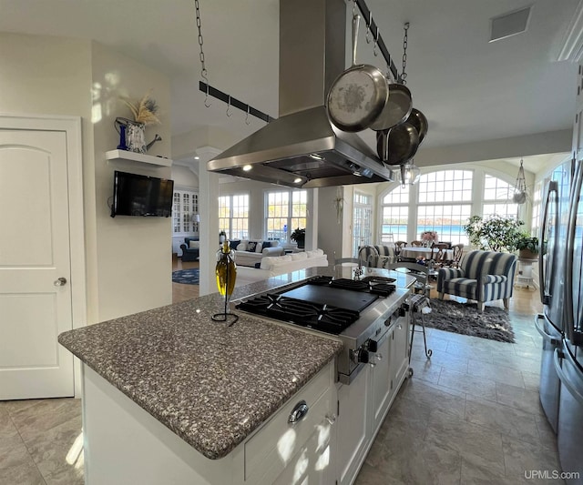 kitchen featuring stainless steel gas cooktop, a healthy amount of sunlight, island range hood, and white cabinets