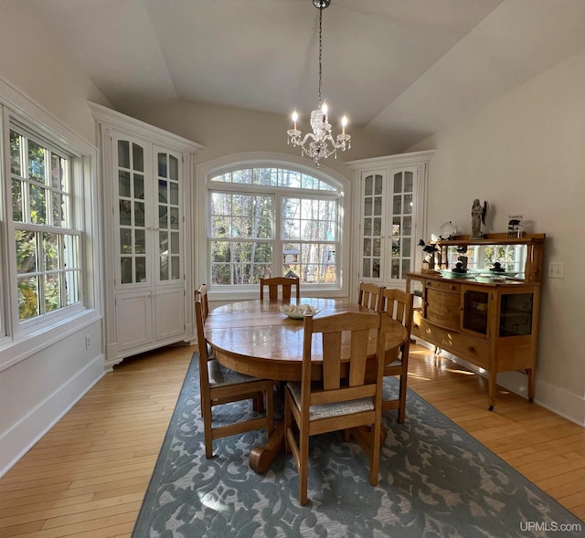 dining space featuring light hardwood / wood-style floors, a healthy amount of sunlight, vaulted ceiling, and a chandelier