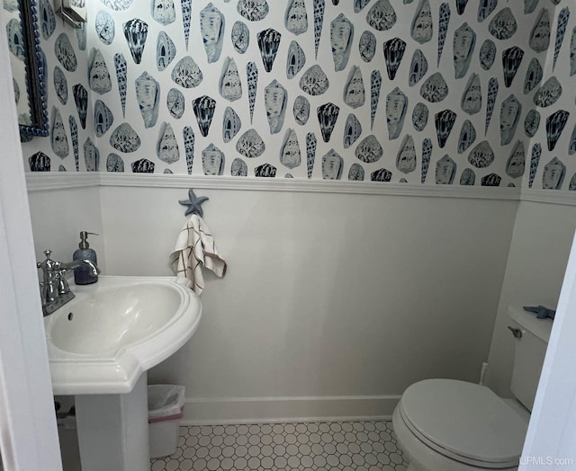 half bath featuring toilet, baseboards, and a sink