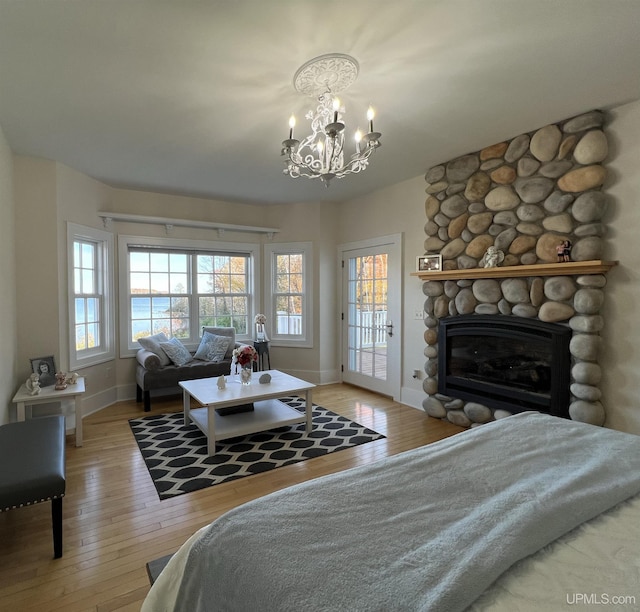 bedroom featuring baseboards, hardwood / wood-style flooring, access to outside, and an inviting chandelier