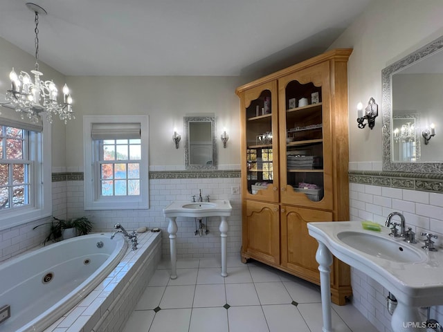 bathroom featuring tile walls, a notable chandelier, tiled tub, and tile patterned flooring