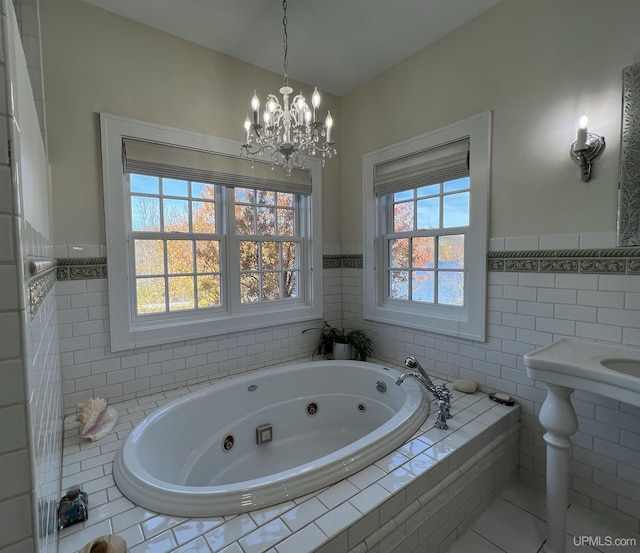 full bath with wainscoting, a tub with jets, a notable chandelier, and tile walls
